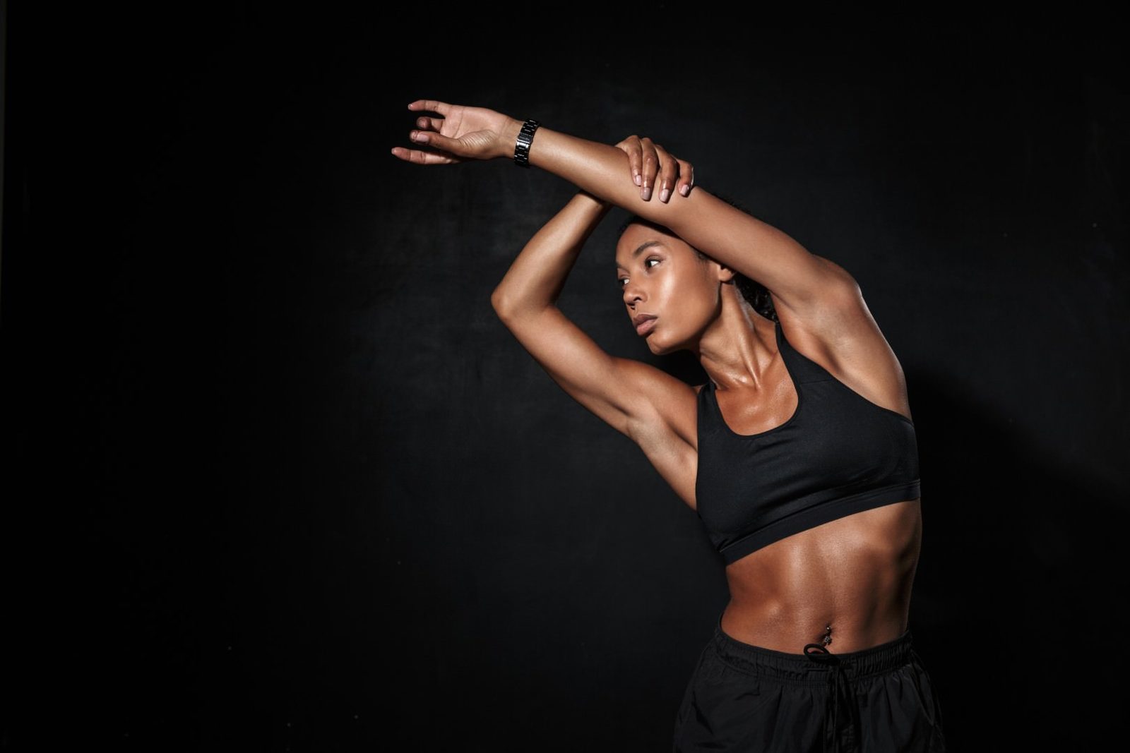 Athlete stretching in activewear against a black background